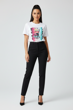 Woman wearing a white t-shirt with a colorful graphic and black pants on a white background