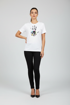 Woman wearing a white t-shirt with a colorful design and black pants on a gray background