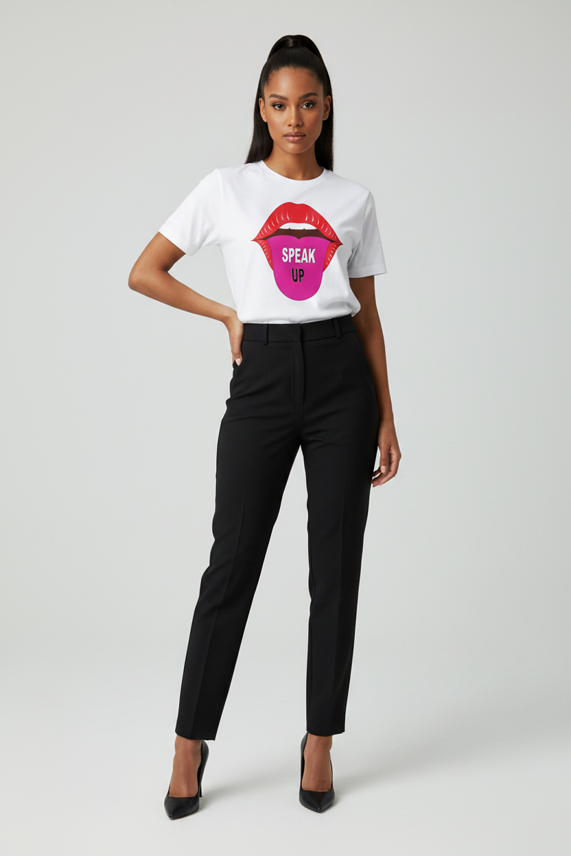 A woman modeling a white graphic T-shirt with a pink and red lips design and the word 'SPEAK UP' on the front, paired with black pants and black heels, against a light gray studio background.
